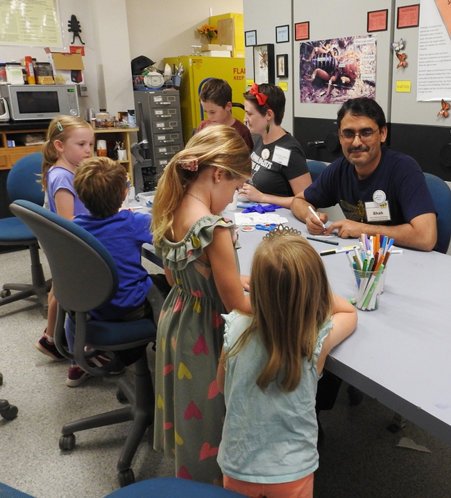 Visiting scholar Syed Fahad Shah and doctoral student Charlotte Herbert Alberts (next to him) help youngsters make buttons at the Bohart Museum of Entomology open house. (Photo by Kathy Keatley Garvey)