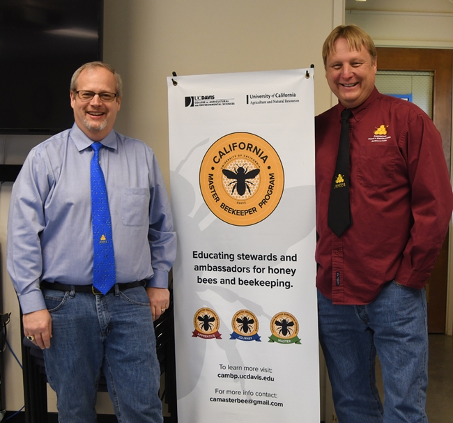 Kelvin Adee (left) of Bruce, S.D.,  president of the American Honey Producers' Association, and past president Darren Cox of Logan, Utah, stand by a California Master Beekeeper Program banner in the Harry H. Laidlaw Jr. Honey Bee Research Facility, UC Davis. (Photo by Kathy Keatley Garvey)