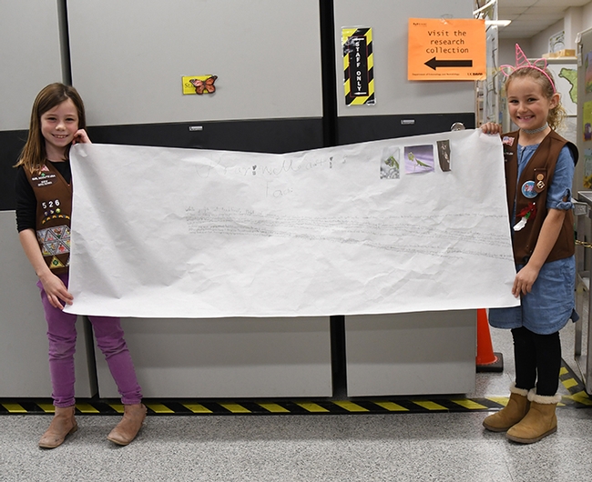 Before Brownie Girl Scout Troop 5520 toured the Bohart Museum, they met to discuss their insect-themed assignments. Here Lauren Wells (left), 7, and Madeline Louis, 8, display a handwritten poster. (Photo by Kathy Keatley Garvey)