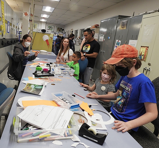 The arts and crafts table at the Bohart Museum featured making tadpole shrimp-themed hats and puppets. At the far left is Tabatha Yang, education and outreach coordinator. (Photo by Kathy Keatley Garvey)