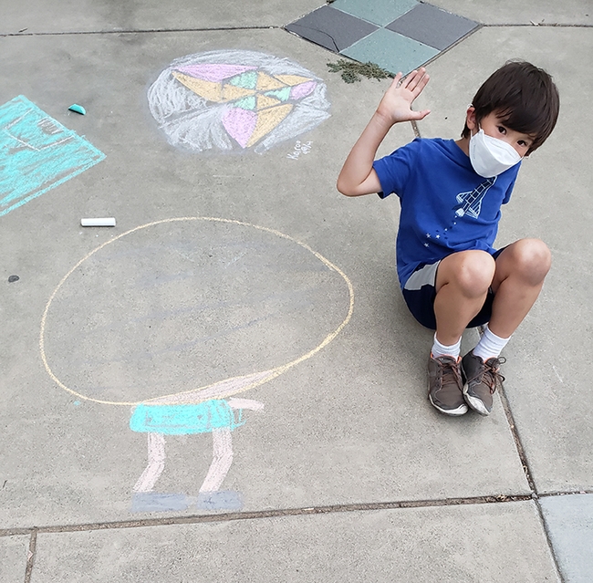 Toco Yang waves to the photographer as he works on his chalk drawing. (Photo by Tabatha Yang)