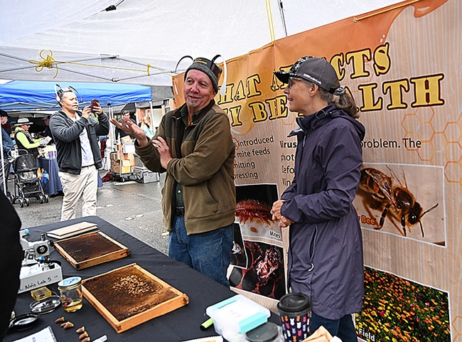 Wendy Mather, co-program manager of the California Master Beekeeper Program (CAMBP) and CAMBP apprentice level Rick Moehrke of Vacaville discuss the merits of beekeeping with festival attendees. Moehrke became a beekeeper last September. (Photo by Kathy Keatley Garvey)