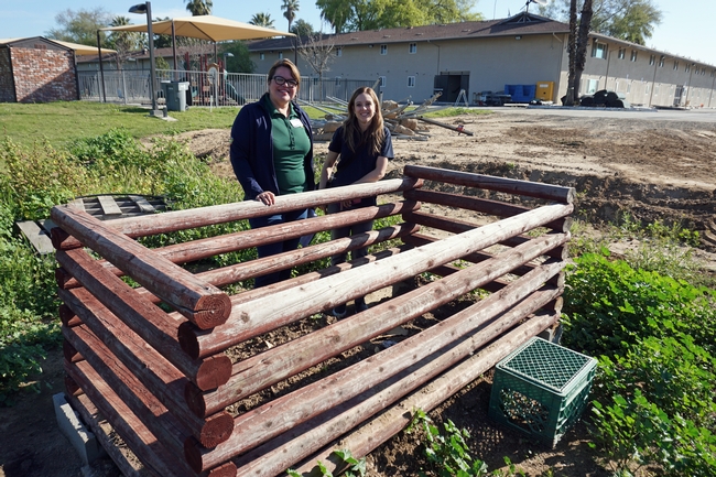 UC CalFresh nutrition educators Nancy Zumkeller, left, and Kristi Sharp stand at the compost bin at Rescue the Children. The residents are learning to compost food scraps, garden trimmings, hair from their brushes, lint from dryers and paper.