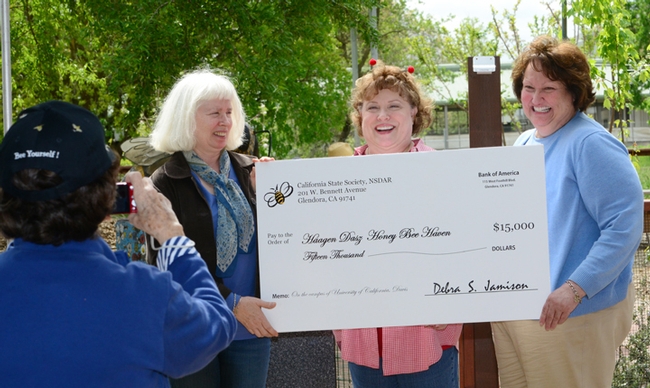 A member of the California State Society of the Daughters of the American Revolution photographs the check presentation. From left are Chris Casey, manager of the haven; Debra Jamison, State Regent of DAR; and Karen Montgomery, the state project chair. (Photo by Kathy Keatley Garvey)