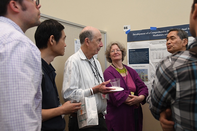 Scientific posters, plus humorous posters, added to the Hammock lab reunion. Here Hammock answers questions from a gathering. (Photo by Kathy Keatley Garvey)