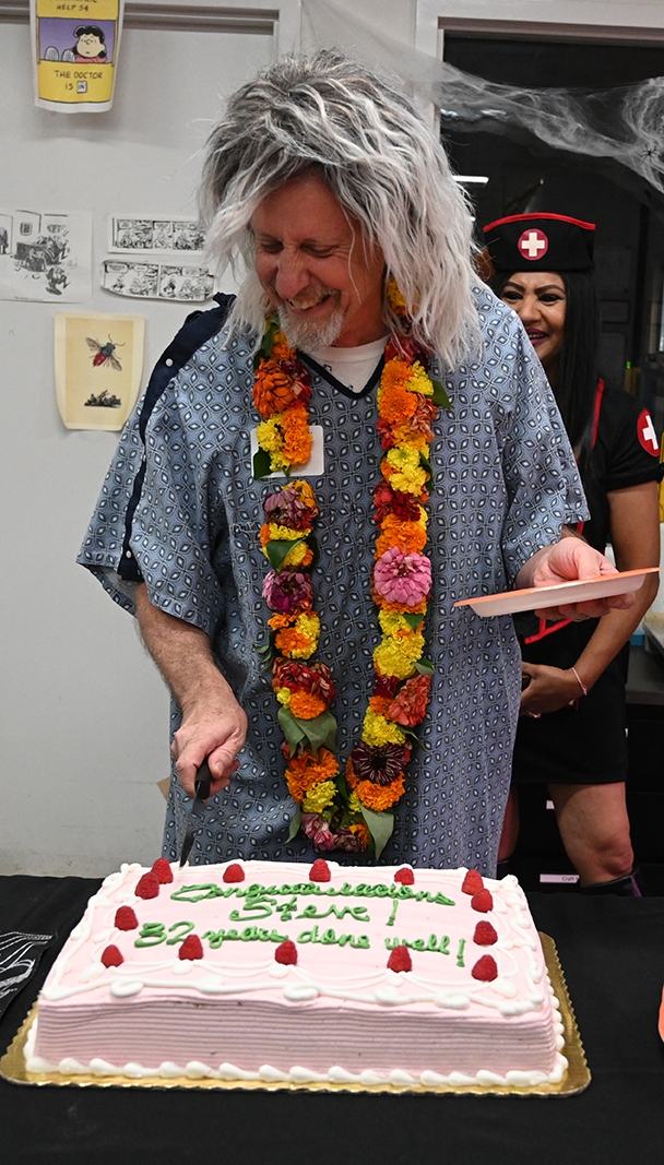 Bohart senior museum scientist Steve Heydon, dressed as a nursing home patient, cuts a cake in honor of his 32 years at UC Davis. He retired at the end of October. (Photo by Kathy Keatley Garvey)