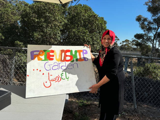 Shahnaz Roshanoi helps paint a welcome sign that says 