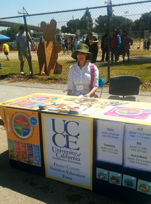 Volunteer Betsy Knapp sitting a Uc CalFresh educational booth at a recent event.