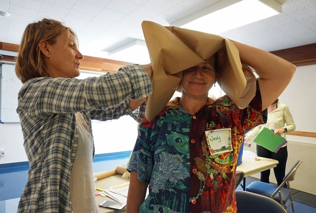 Trainees Carla Rosin, right, and Wendy Minarik work on a paper and tape hat.