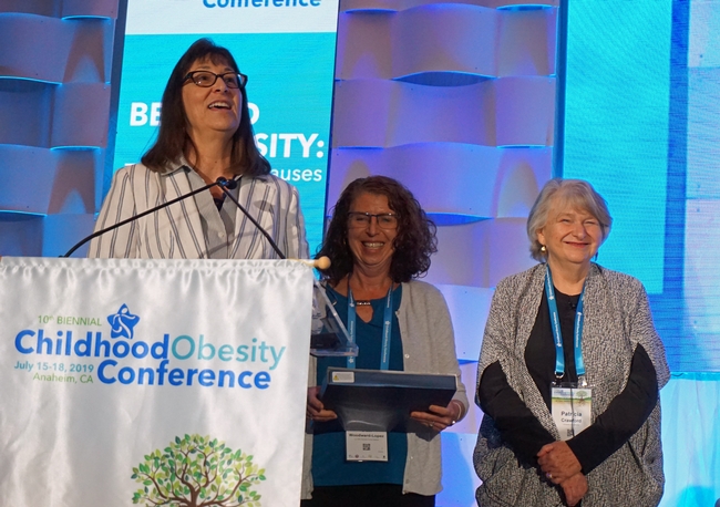 NPI director Lorrene Ritchie, left, and NPI associate director of research Gail Woodward-Lopez, honor NPI senior director of research emeritus Patricia Crawford (right) at the Childhood Obesity Conference.