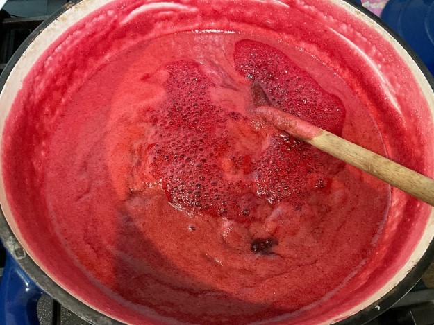 Pot of boiling raspberries with wooden spoon