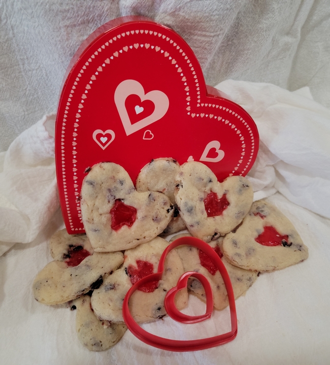 Red heart in the background. Heart shaped cookies on a white table cloth