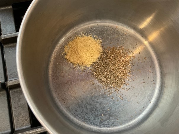 Ground spices toasting in a pan.