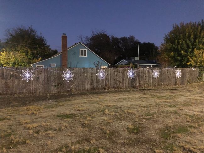 6 white plastic hanger snowflakes on a fence with white led lights