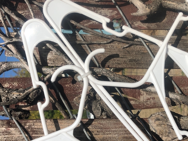 Close-up of portions of 4 white plastic hangers and a connecting clear zip tie