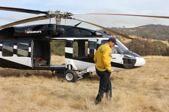 A helicopter equipped with a water bucket specially designed for use in fire fighting is ready on site in case the blaze gets out of control.
