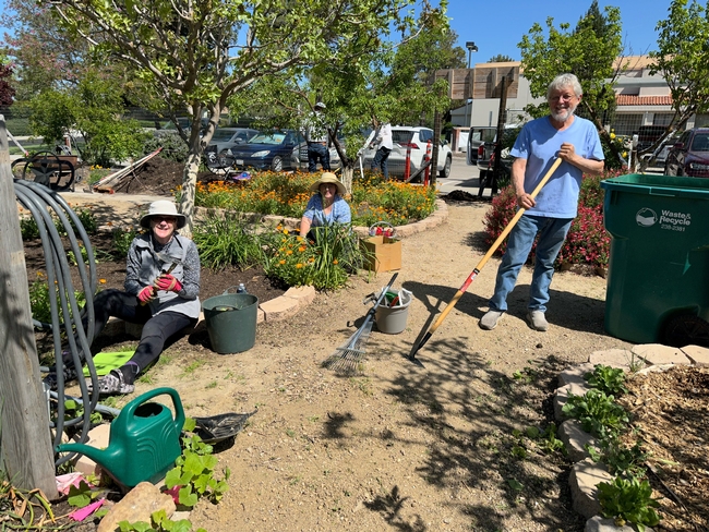 three volunteers smile as they work in the demonstration garden
