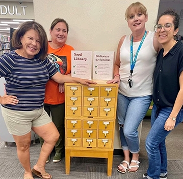 Group of Gardeners standing around a seed library