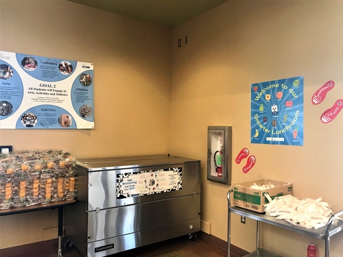 Healthful posters and decals are hung on the wall and a poster promoting the benifits of milk is posted on the outside of the milk cooler.