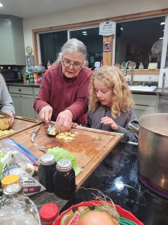 4-H volunteer instructing a youth while cooking