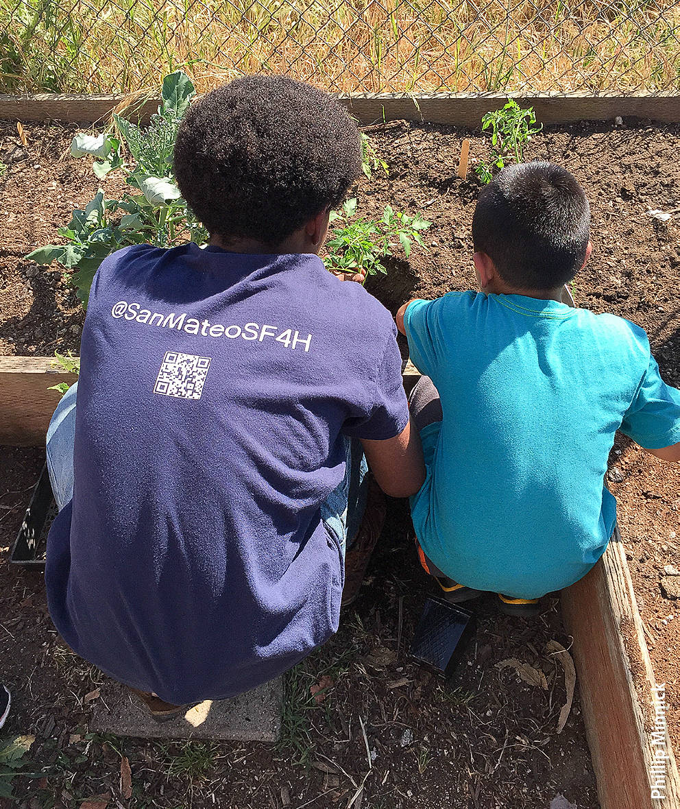 An HLA teen talks with an elementary school student about growing vegetables. Teens as peer educators can be as effective as adult teachers in prompting healthy behaviors in children.