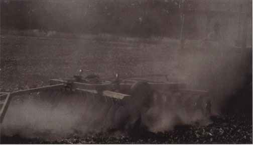 Disking with an open-cabin tractor in the morning after the wheat harvest. Duplicate samplers are visible in the middle of the disk. Scientists measured emissions of respirable dust at the source, not downwind. Concentrations decrease markedly downwind from the source as dust is dispersed in the atmosphere and diluted.