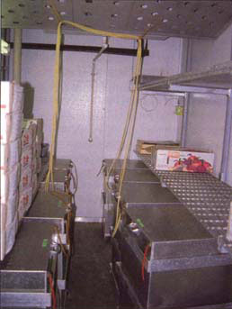 Controlled environment room with aluminum tanks containing boxes of peaches. Controlled atmospheres prepared with the mixing board were introduced into the tanks.