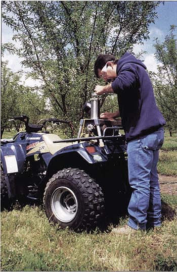 Mario Salinas takes pressure chamber measurements with the console model used in this study. This relatively large type of pressure chamber can be mounted on an all-terrain cycle for easy orchard access.