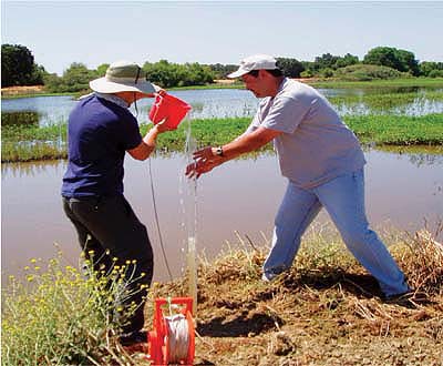 UC Davis graduate student John Maynard (left) and UC Cooperative Extension specialist Toby O'Geen examine the effects of wetland treatment for water-quality improvement of irrigation tailwaters in western Stanislaus County. As shown by the transparency tube, suspended solids are effectively removed by treatment in flow-through wetlands. The transparency tube provided accurate measurements of water transparency, and is a low-cost tool that is easy to use in the field.