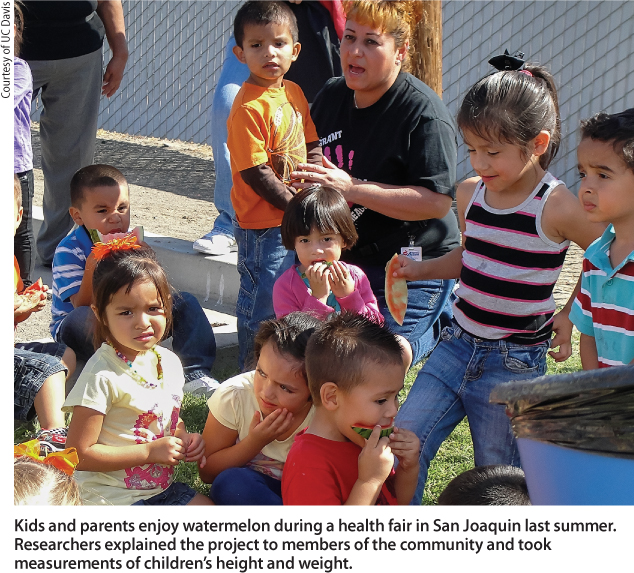 Kids and parents enjoy watermelon during a health fair in San Joaquin last summer. Researchers explained the project to members of the community and took measurements of children's height and weight.