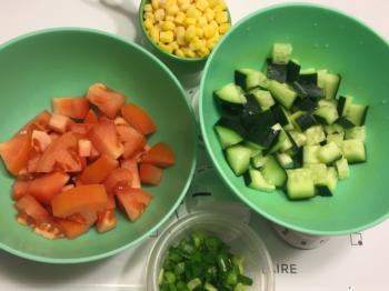 Prepare toppings while pasta cooks: 1 small tomato (diced), 1/2 cucumber (diced), 1/2 cup corn, 2 green onions (chopped)