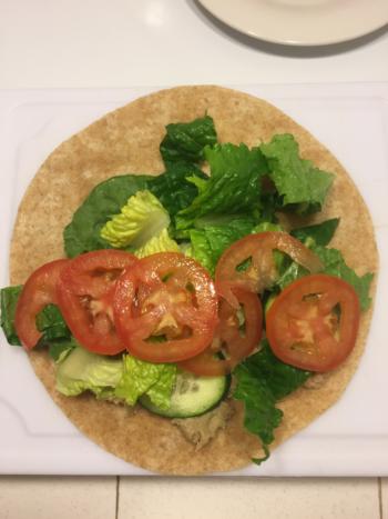 Tuna on whole wheat tortilla topped with cucumbers, lettuce, and tomatoes