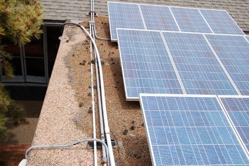Solar panels installed on a flat roof with accumulated debris