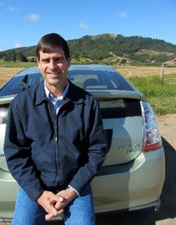 David Lewis, current Director and Farm Advisor, sitting on the bumper of a Toyota Prius, 2012