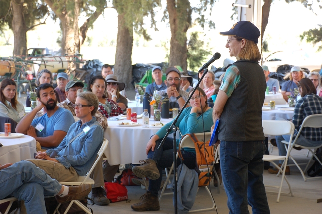 Woman wearing an ANR hat speaks to a group of people sitting around round tables.