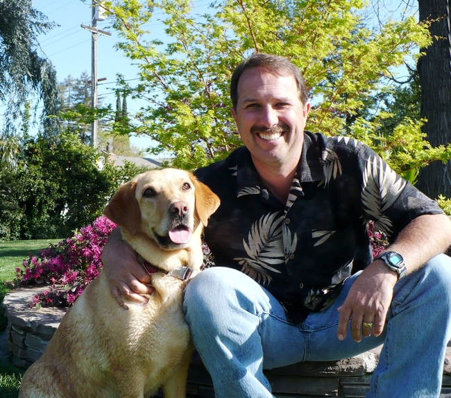 Roger sits beside his dog, a golden lab.