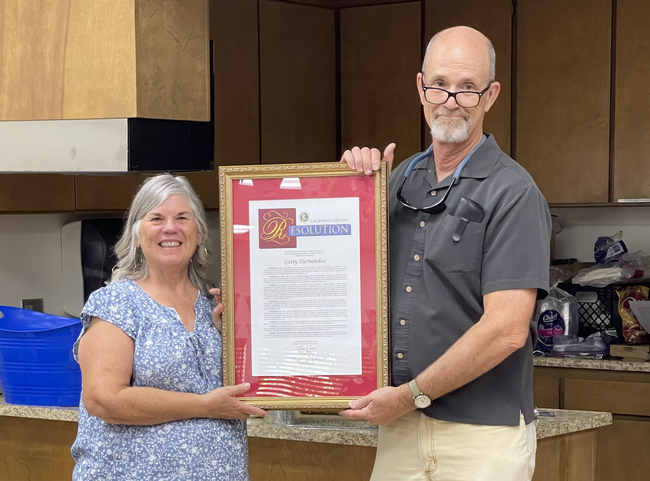 Gerry and Franz stand holding opposite sides of the large, framed document.