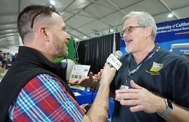Kearney REC director Jeff Dahlberg shares research news with a reporter at the World Ag Expo.
