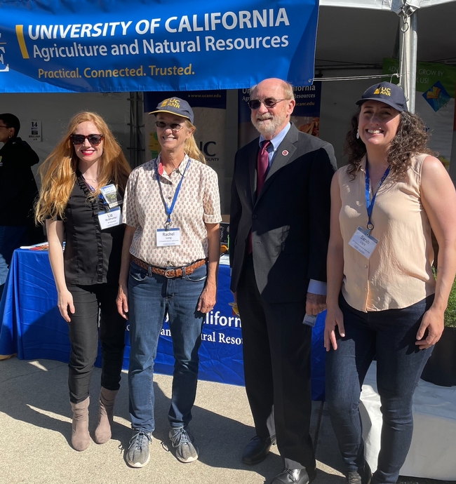 The four are standing in front of the Master Gardener booth under a banner that reads: University of California Agriculture and Natural Resources. Practical. Connected. Trusted.