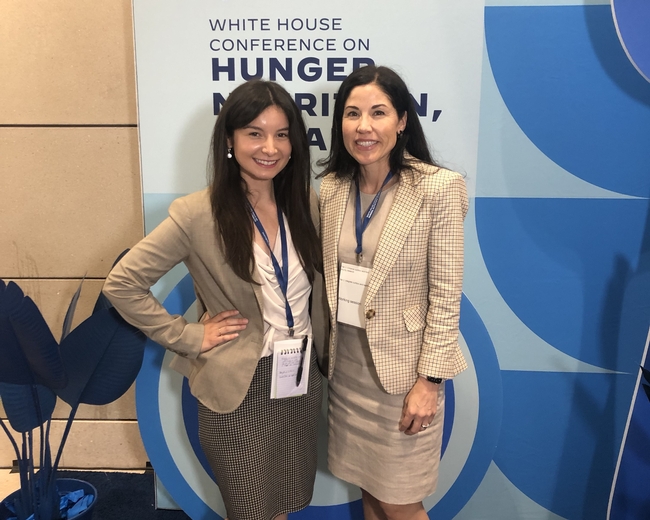Suzanna Martinez and Jocelyn Villalobos pose with White House conference on hunger, nutrition, health banner.