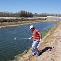 A man samples irrigation water. The water itself may contain nitrogen.