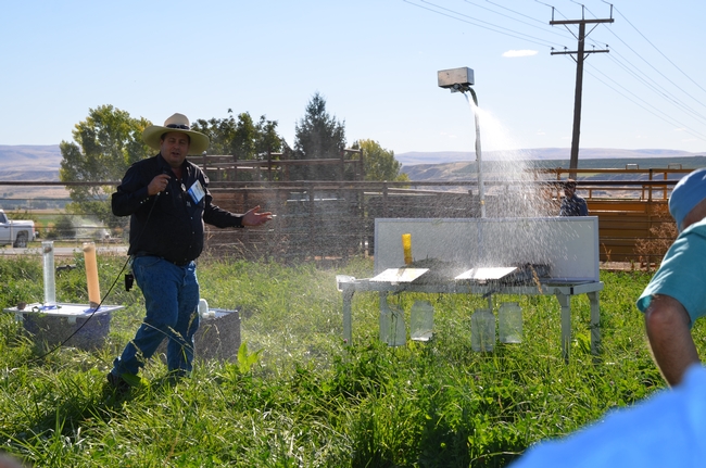 A rainfall simulator sprays water over trays of different soils to show how on-farm management practices affect soil health.