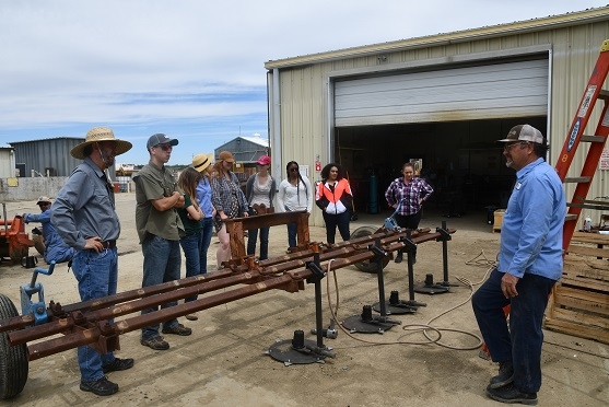 Nine NRCS and UC ANR soil health experts meeting with Senior Mechanic, Mark Strole, who is showing the new cover crop cutter that is being tried in the NRI Project field this spring