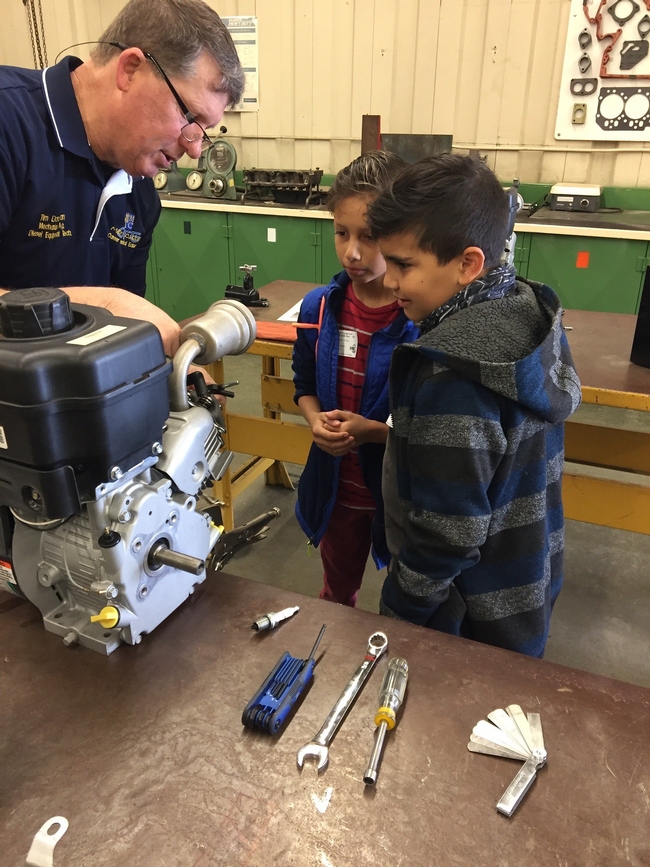 Adult volunteer with youth learning about small engines.