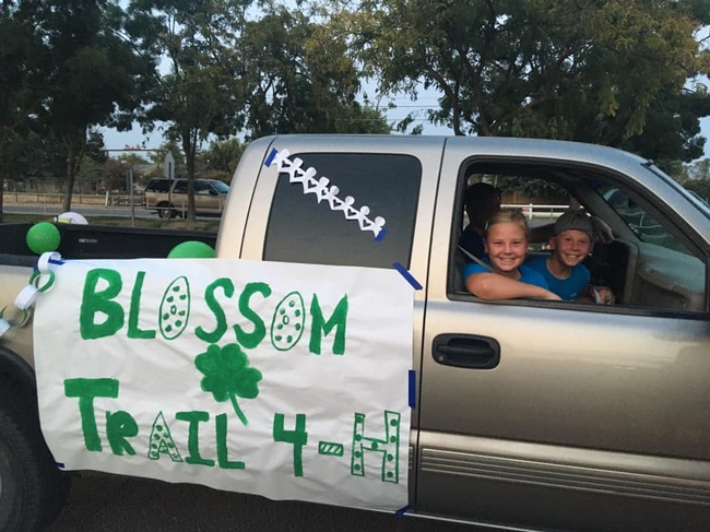 Truck decorated with Blossom Trail 4-H banner with 2 youth looking out window.
