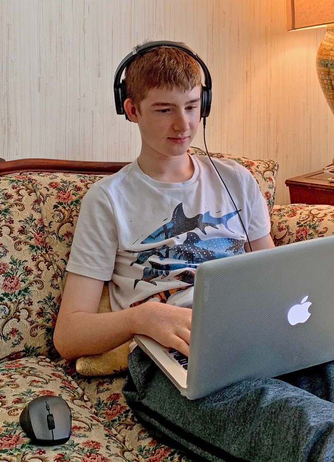 Youth with headphones looking at laptop
