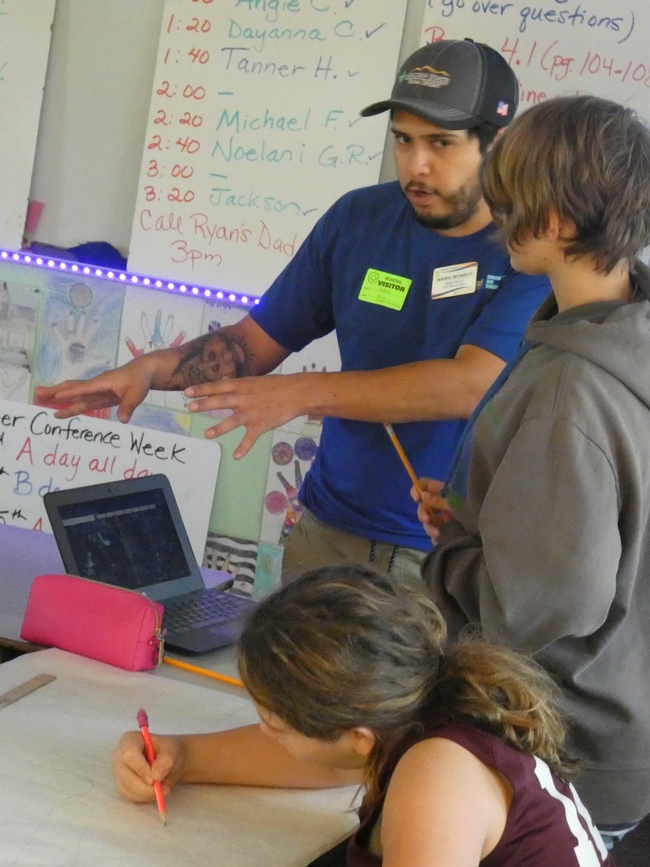 An educator instructs a student in a classroom