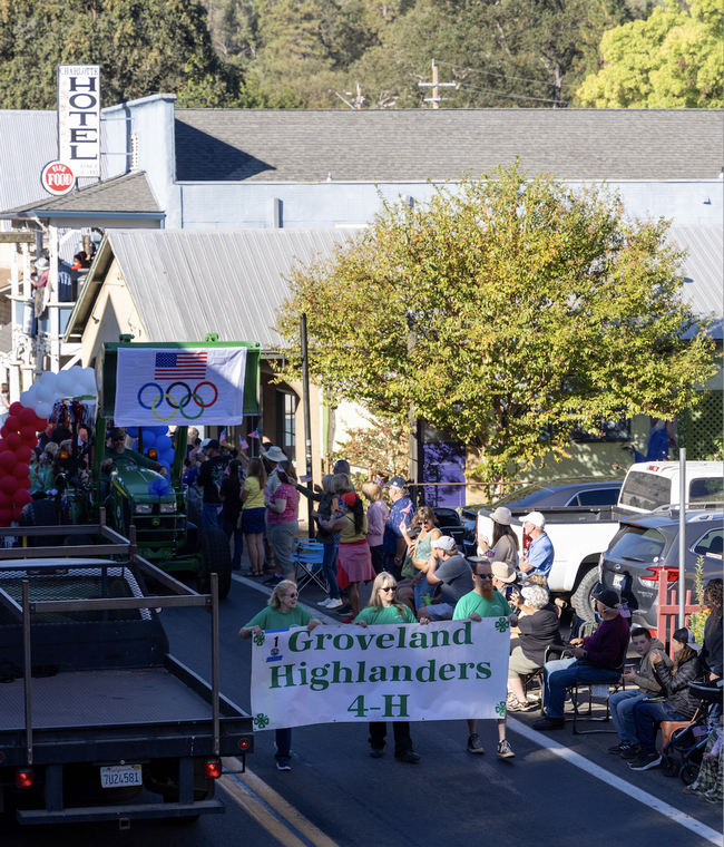 Three people in green shirts carry a banner that reads, 