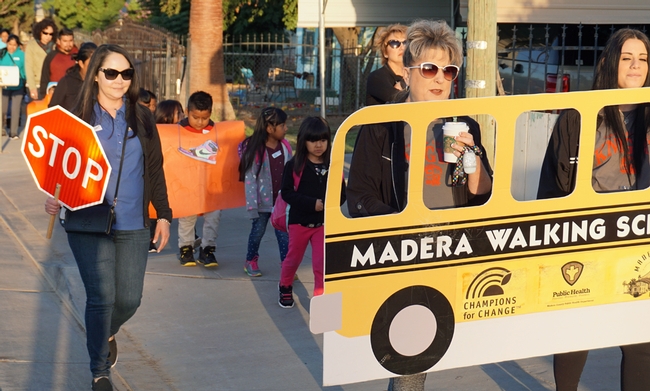 UC CalFresh manager Karina Macias, left, leads the Virginia Lee students along with teachers Carolyn Lozano and Aubrey Rutherford (left to right, holding the school bus banner.)