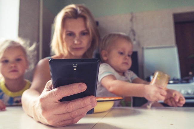 Woman on a smartphone while caring for children